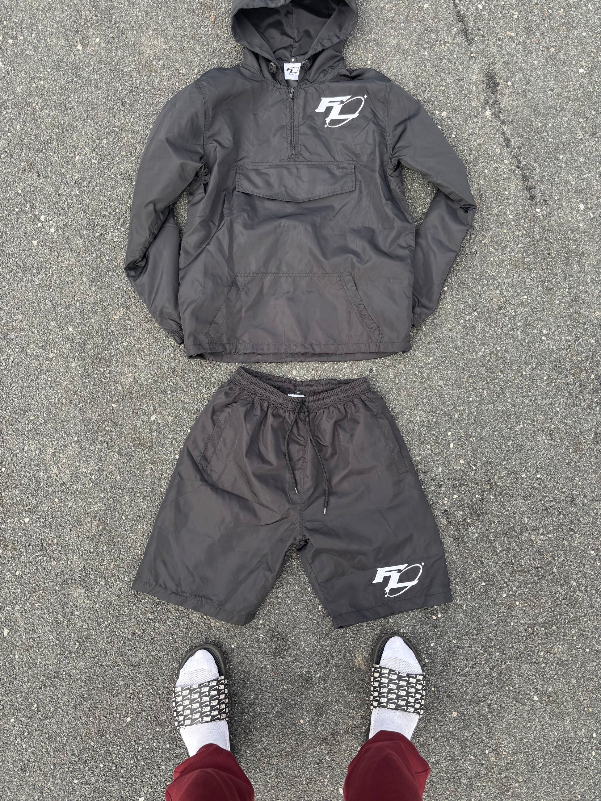 Black jacket and pants with a logo on a gray pavement